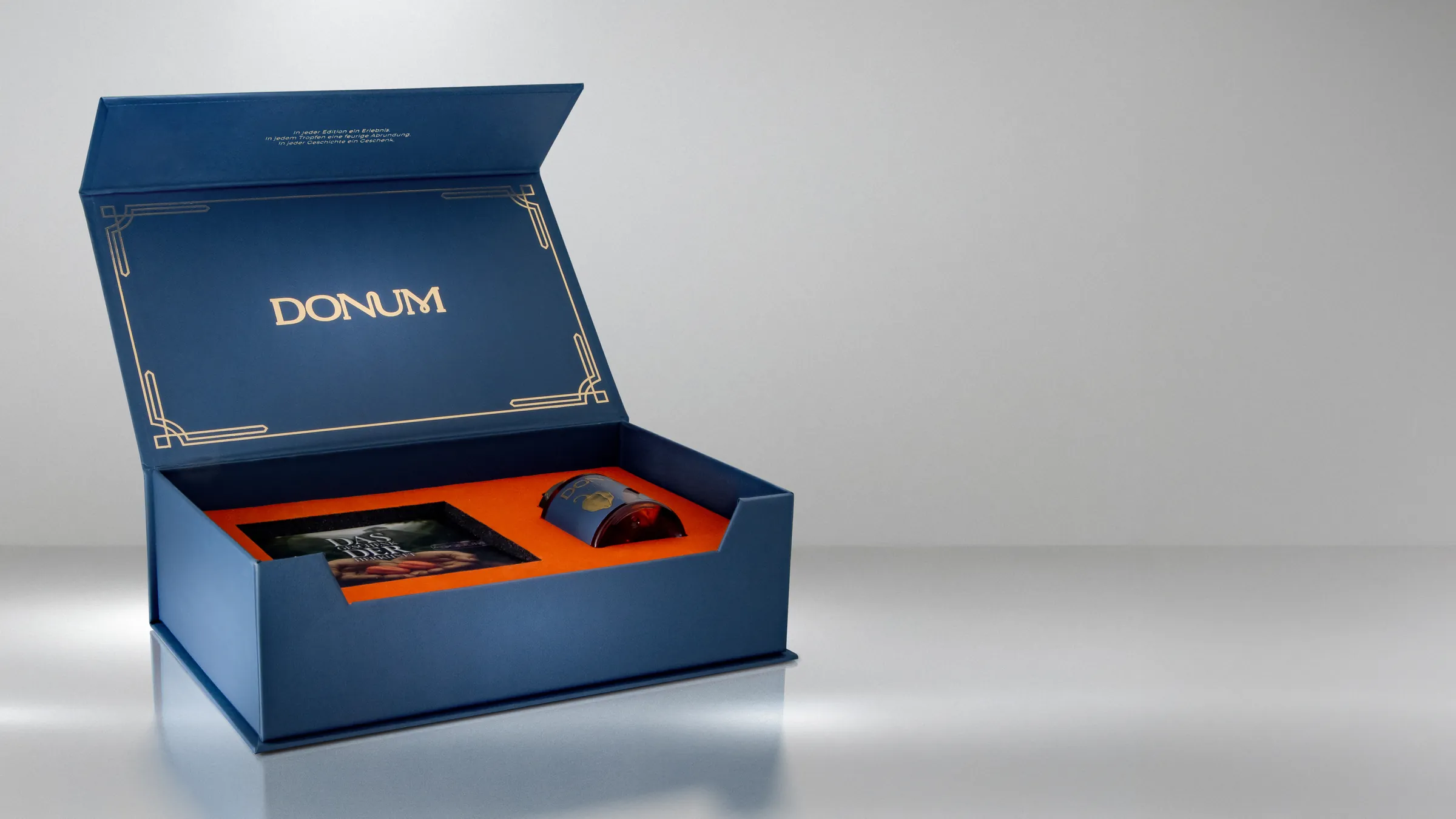 Die geoeffnete DONUM Geschenkbox mit Booklet und eingelegtem Flakon